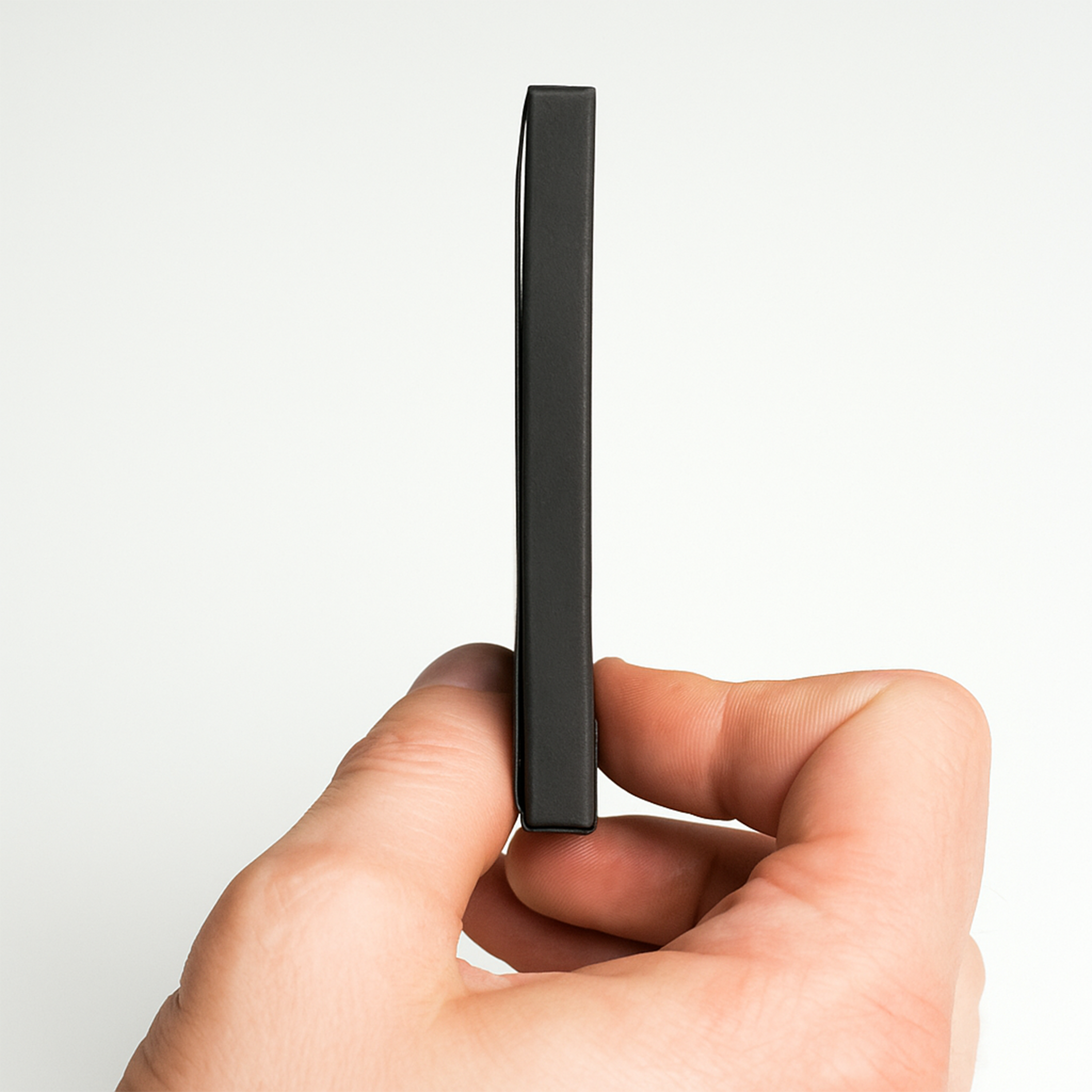 Side profile view of a hand holding a slim, black PullShield protective sleeve, highlighting its thin and compact design.