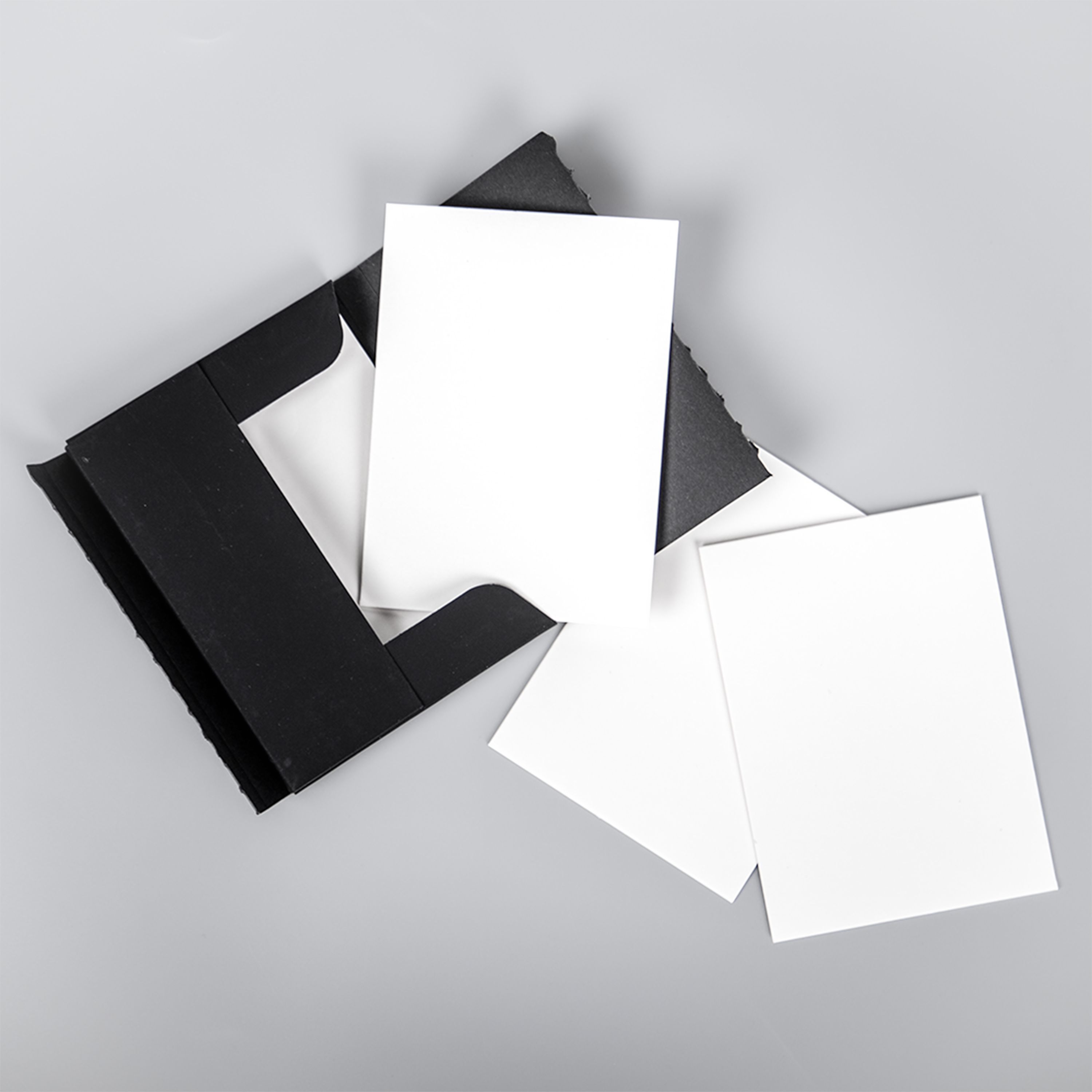 Open PullShield protective sleeve displayed with multiple white cardboard inserts partially inside and scattered around, showing the included protective layers for card shipping.